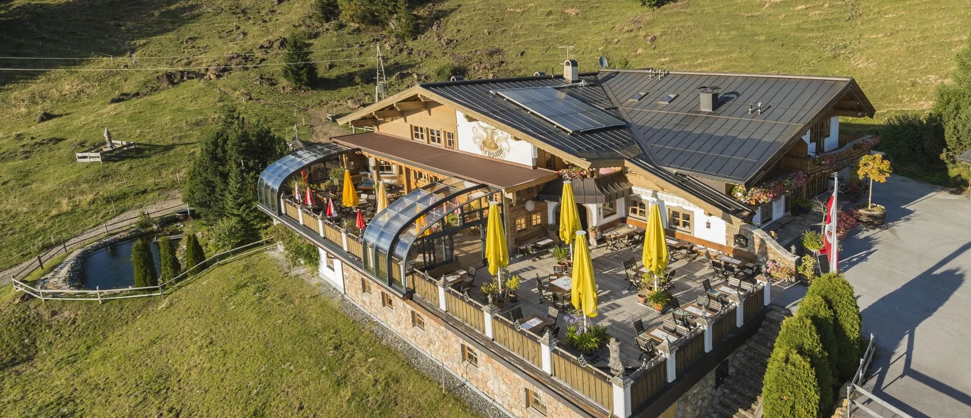 OchsAlm in der Abendsonne — Terrasse mit gelben Sonnenschirmen über Kirchberg