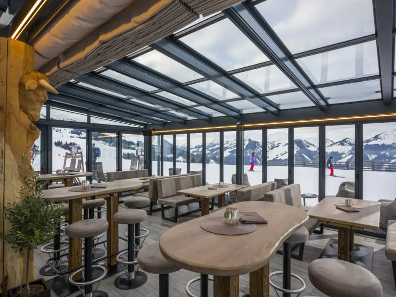 Verglaster Wintergarten der OchsAlm mit Blick auf die verschneiten Berge