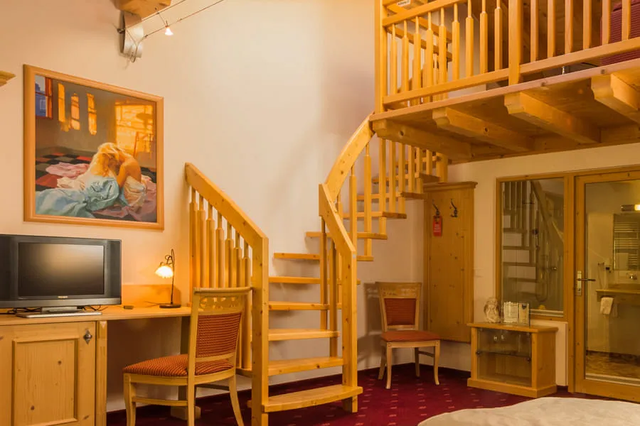Suite Rettenstein – Wohnbereich mit Holzstiege zur Galerie